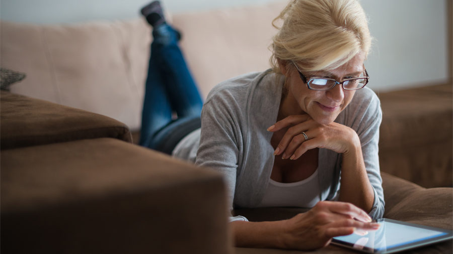 Femme sur sa tablette en train de faire des réglages pour son logement connecté